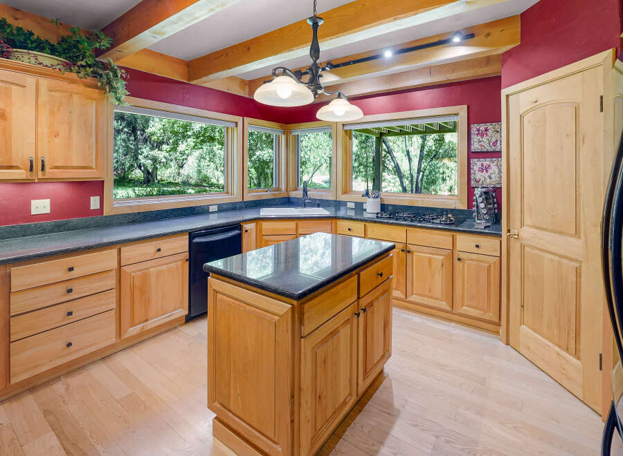 This spacious kitchen boasts custom light wood cabinetry and granite countertops, offering ample storage and workspace.