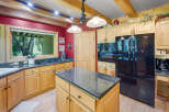 This spacious kitchen features warm, light wood cabinetry complemented by a striking red accent wall and exposed wooden beams.