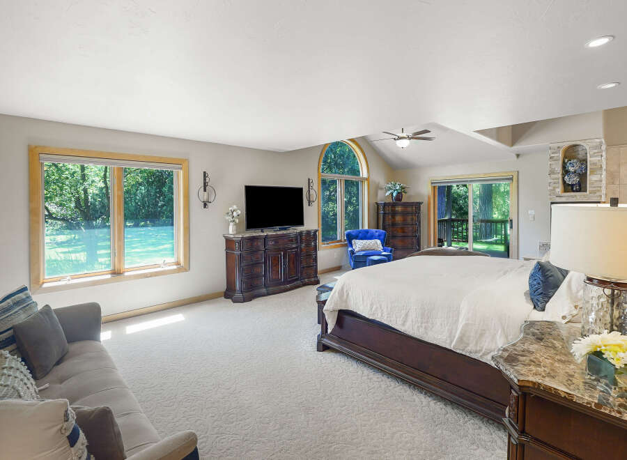 Experience luxury and comfort in this spacious master bedroom, featuring a plush king-sized bed and a cozy seating area with a sofa and armchair.