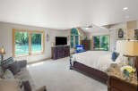 Experience luxury and comfort in this spacious master bedroom, featuring a plush king-sized bed and a cozy seating area with a sofa and armchair.