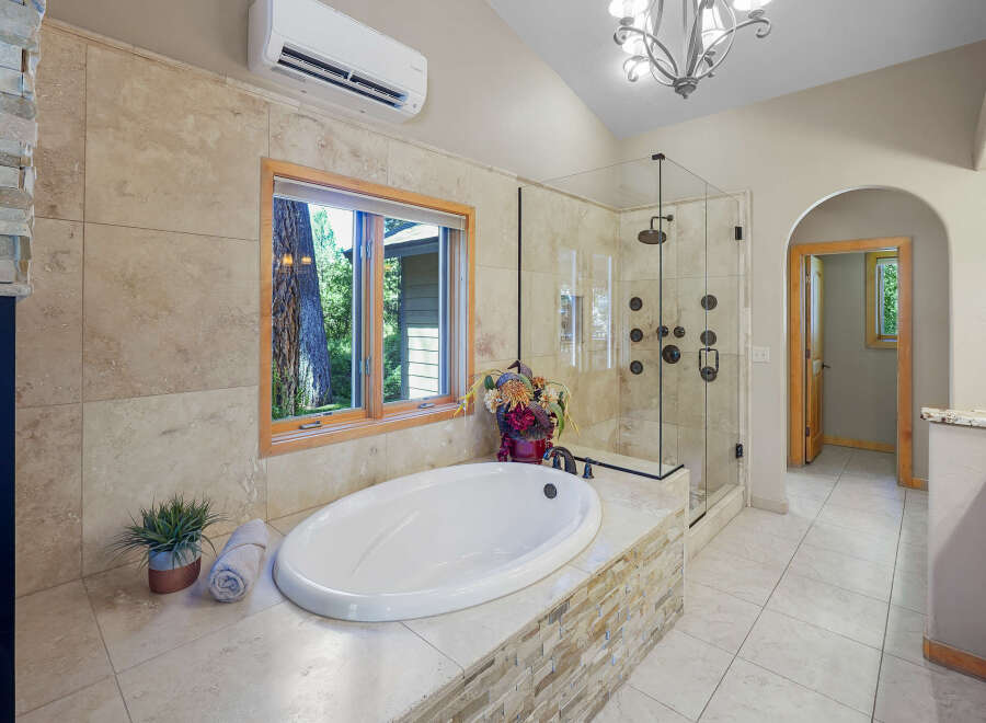 Indulge in luxury in this stunning bathroom featuring a spacious soaking tub with a view of the lush outdoors.