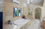 Indulge in luxury in this stunning bathroom featuring a spacious soaking tub with a view of the lush outdoors.