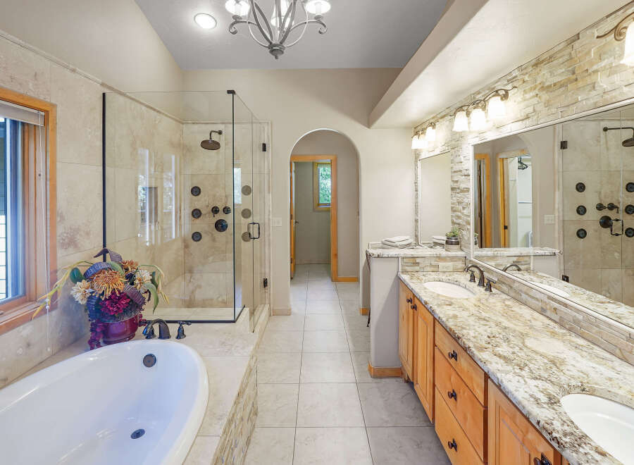 Indulge in luxury with this stunning master bathroom, featuring a spacious walk-in shower with multiple shower heads and a deep soaking tub perfect for relaxation.