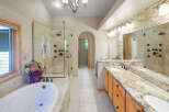 Indulge in luxury with this stunning master bathroom, featuring a spacious walk-in shower with multiple shower heads and a deep soaking tub perfect for relaxation.