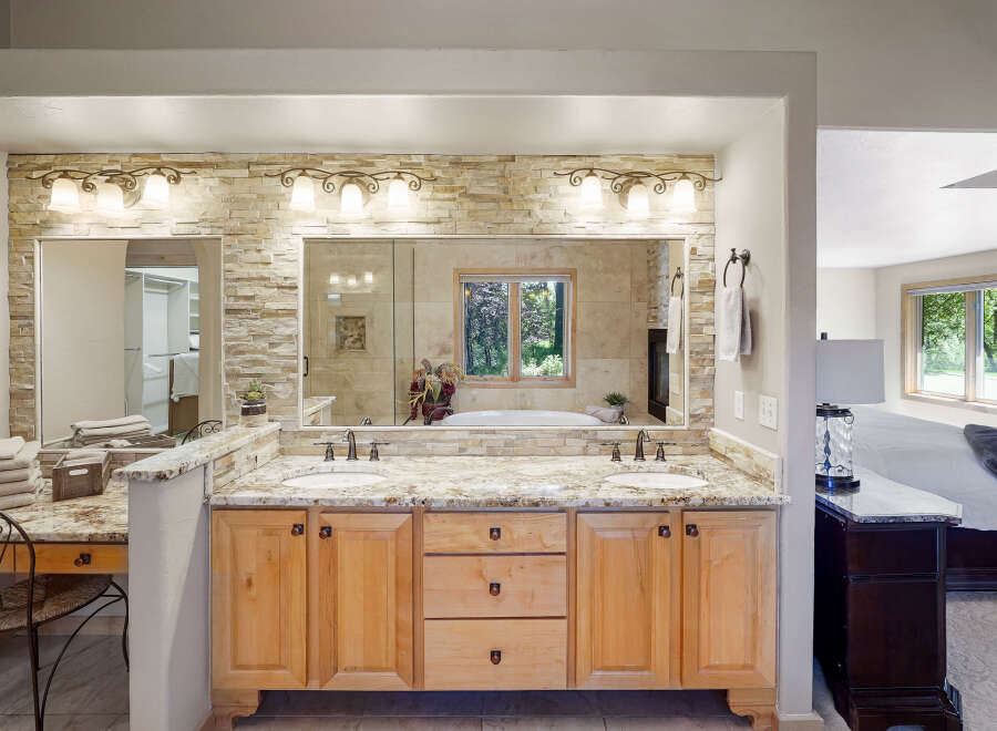 Experience luxury in this stunning master bathroom featuring a spacious double vanity with granite countertops and elegant stone tile backsplash.