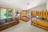 This spacious bedroom is perfect for families or groups, featuring two sets of sturdy wooden bunk beds and a comfortable leather sofa.