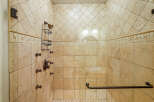 Experience luxury in this spacious walk-in shower, featuring elegant travertine tile and a multi-head shower system for a spa-like experience.
