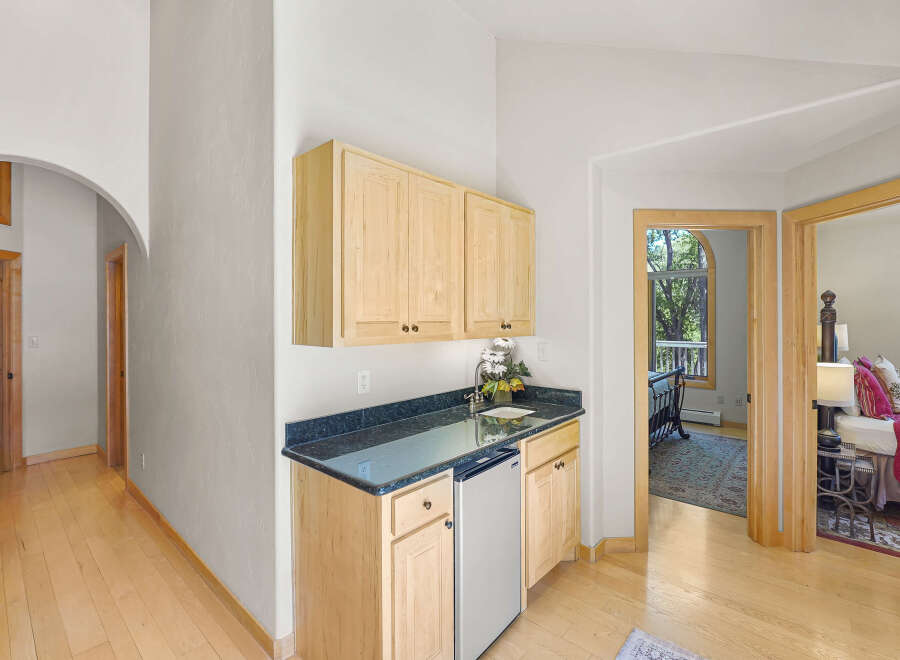 Discover this charming wet bar area featuring light wood cabinetry and a dark granite countertop, perfect for entertaining.