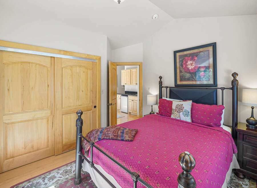 This charming bedroom features a comfortable queen-size bed with a vibrant pink quilt and decorative pillows.