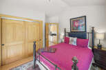 This charming bedroom features a comfortable queen-size bed with a vibrant pink quilt and decorative pillows.