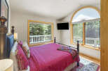 Experience serene mountain living in this charming bedroom, featuring a comfortable queen-size bed adorned with a vibrant pink quilt and decorative pillows.