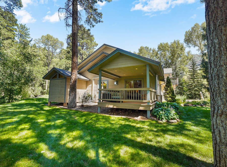 Nestled amidst lush greenery, this charming home offers a serene retreat with its inviting covered porch and expansive lawn.