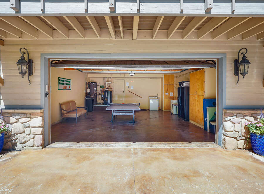 This spacious garage offers a versatile space for recreation and storage, featuring a ping pong table for entertainment and ample cabinetry for organization.