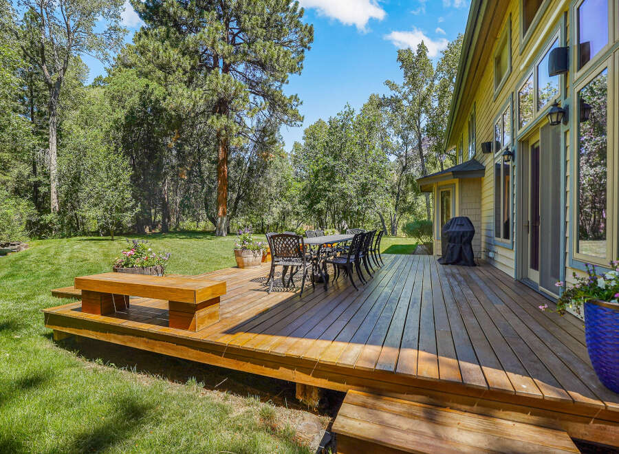 Enjoy outdoor living on this expansive wooden deck, perfect for entertaining or relaxing amidst lush greenery.