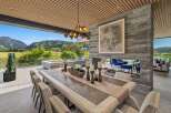 Experience luxurious indoor-outdoor living with this stunning dining area, featuring a large wooden table set for a feast.