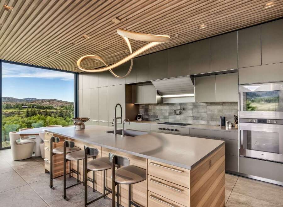 Experience modern luxury in this stunning kitchen featuring a sleek island with bar seating and a unique sculptural pendant light.