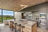 Experience modern luxury in this stunning kitchen featuring a sleek island with bar seating and a unique sculptural pendant light.