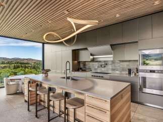 Experience modern luxury in this stunning kitchen featuring a sleek island with bar seating and a unique sculptural pendant light.