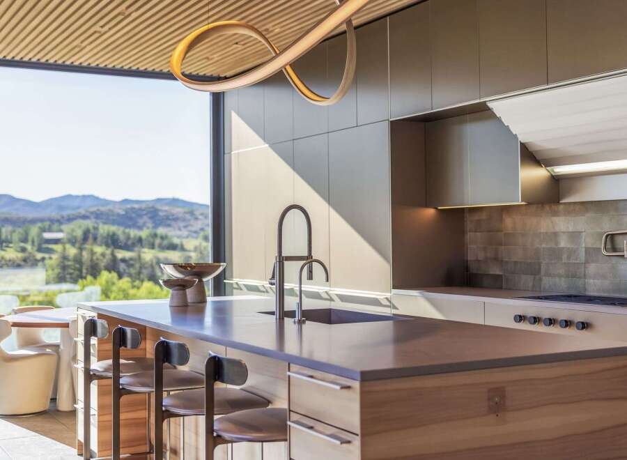 Experience luxury living in this modern kitchen featuring a sleek island with a waterfall countertop and integrated sink.