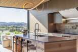 Experience luxury living in this modern kitchen featuring a sleek island with a waterfall countertop and integrated sink.