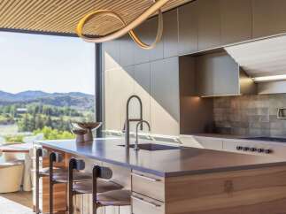 Experience luxury living in this modern kitchen featuring a sleek island with a waterfall countertop and integrated sink.