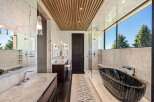 Experience ultimate luxury in this spa-like bathroom, featuring a stunning black marble bathtub with a sleek chrome faucet.