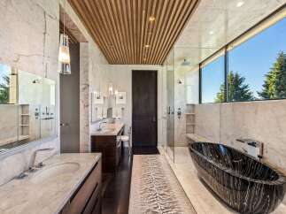 Experience ultimate luxury in this spa-like bathroom, featuring a stunning black marble bathtub with a sleek chrome faucet.