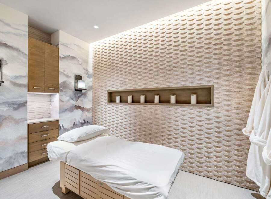 Experience ultimate relaxation in this serene spa room, featuring a comfortable massage bed and a beautifully textured accent wall.