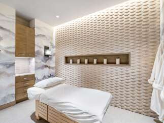 Experience ultimate relaxation in this serene spa room, featuring a comfortable massage bed and a beautifully textured accent wall.