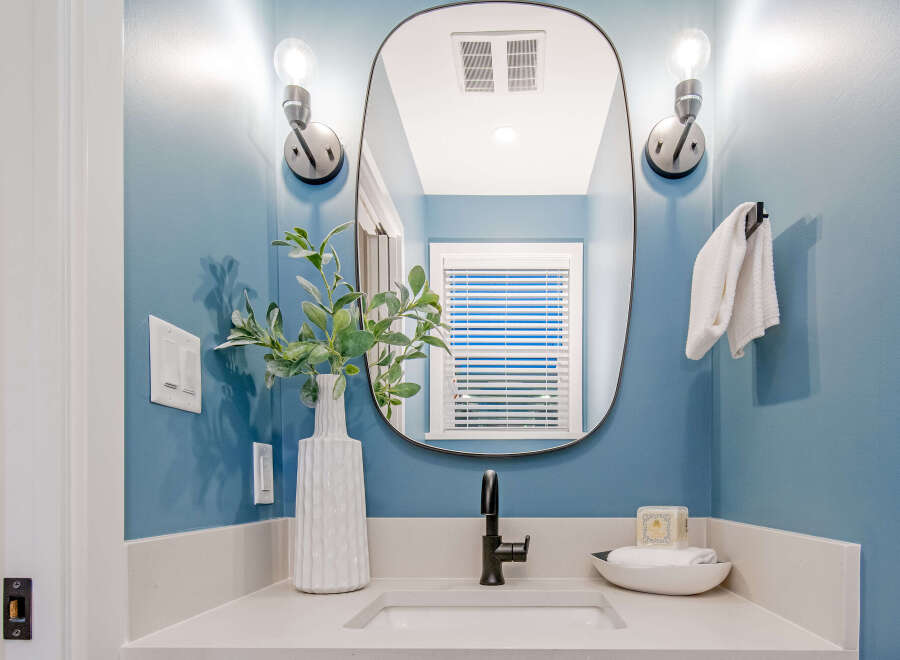 This modern bathroom features a sleek vanity with a white countertop and a matte black faucet.