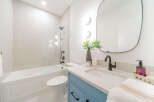 This modern bathroom features a sleek white subway tile shower and tub combination, complemented by a stylish blue vanity with black hardware.