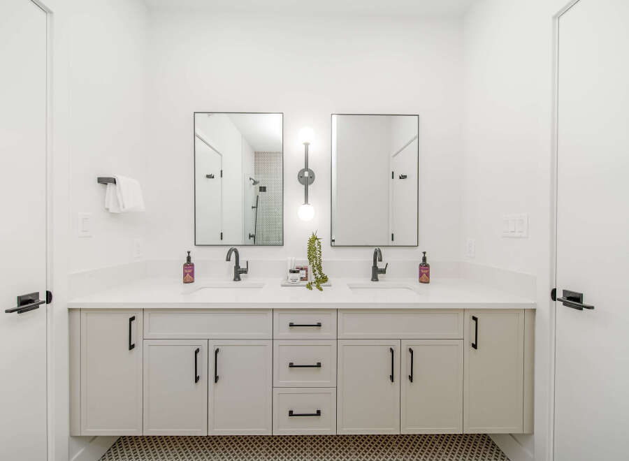 This modern bathroom features a spacious double vanity with sleek black fixtures and ample storage.
