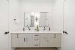 This modern bathroom features a spacious double vanity with sleek black fixtures and ample storage.