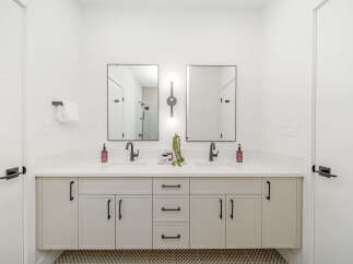 This modern bathroom features a spacious double vanity with sleek black fixtures and ample storage.
