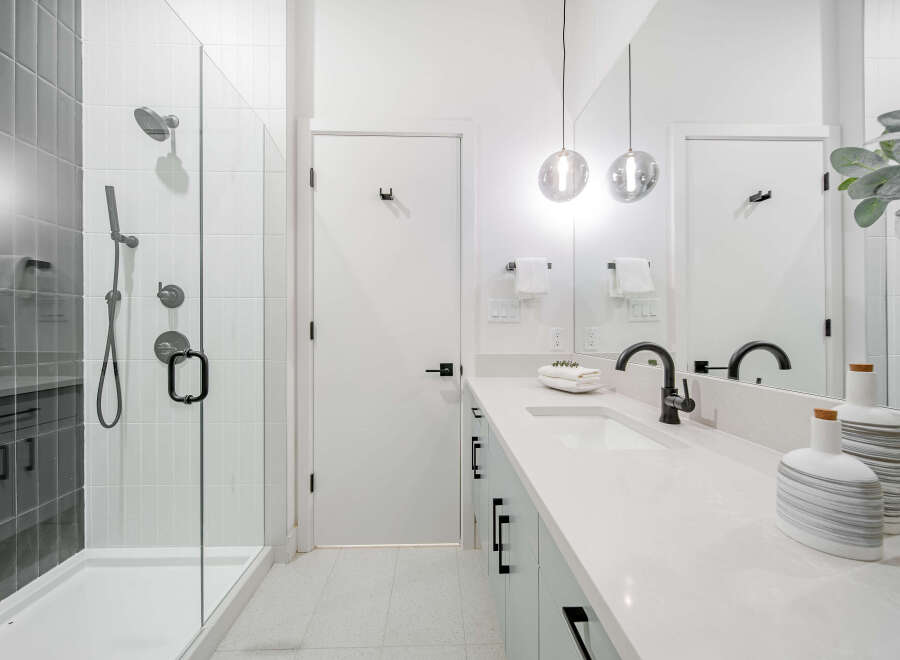 Experience modern luxury in this stunning bathroom, featuring a sleek glass-enclosed shower with elegant tile work and a spacious vanity with a minimalist design.