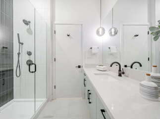 Experience modern luxury in this stunning bathroom, featuring a sleek glass-enclosed shower with elegant tile work and a spacious vanity with a minimalist design.