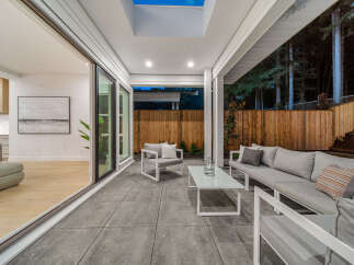 Experience seamless indoor-outdoor living with this stunning covered patio, featuring a modern outdoor seating area perfect for relaxation and entertaining.