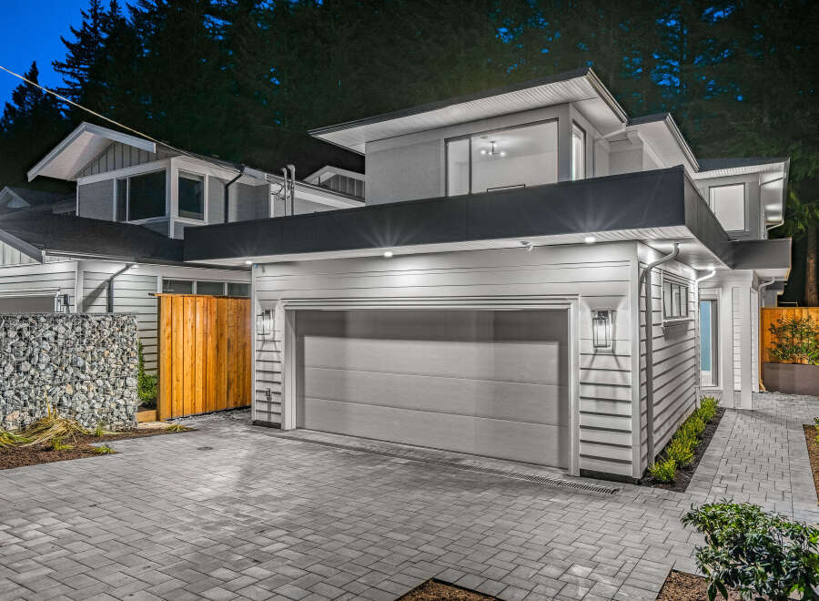 Modern architecture meets natural beauty in this stunning home, featuring a sleek grey garage door and contemporary siding.