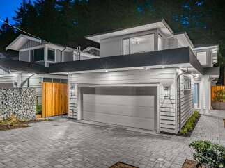 Modern architecture meets natural beauty in this stunning home, featuring a sleek grey garage door and contemporary siding.