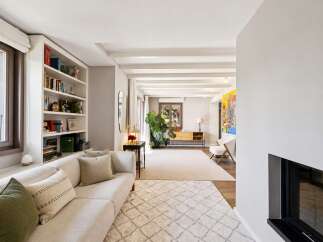 This spacious living room features a comfortable sectional sofa, a built-in bookshelf filled with decorative items and books, and a large window offering natural light.