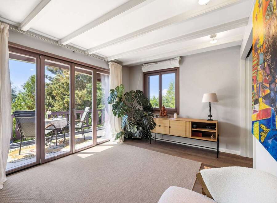 Step into this inviting living space featuring expansive sliding glass doors that open to a charming balcony, perfect for enjoying the lush green surroundings.