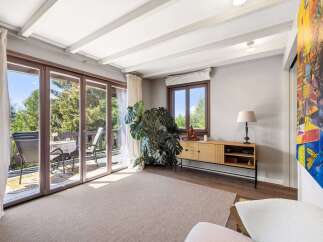 Step into this inviting living space featuring expansive sliding glass doors that open to a charming balcony, perfect for enjoying the lush green surroundings.