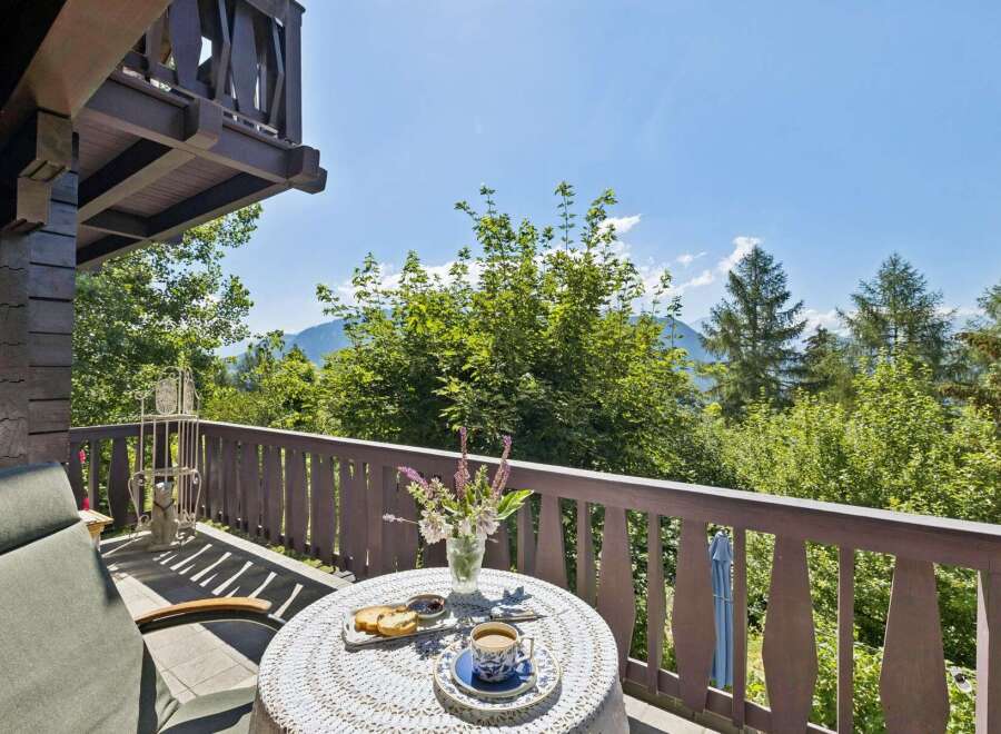 Enjoy your morning coffee on this charming balcony with a breathtaking view of lush greenery and distant mountains.