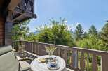 Enjoy your morning coffee on this charming balcony with a breathtaking view of lush greenery and distant mountains.