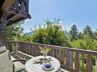 Enjoy your morning coffee on this charming balcony with a breathtaking view of lush greenery and distant mountains.