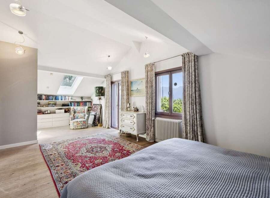 This charming bedroom features a vaulted ceiling with skylights, flooding the space with natural light.