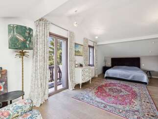 This charming bedroom features a large, comfortable bed adorned with a textured grey duvet, perfectly complemented by a vibrant Persian rug.