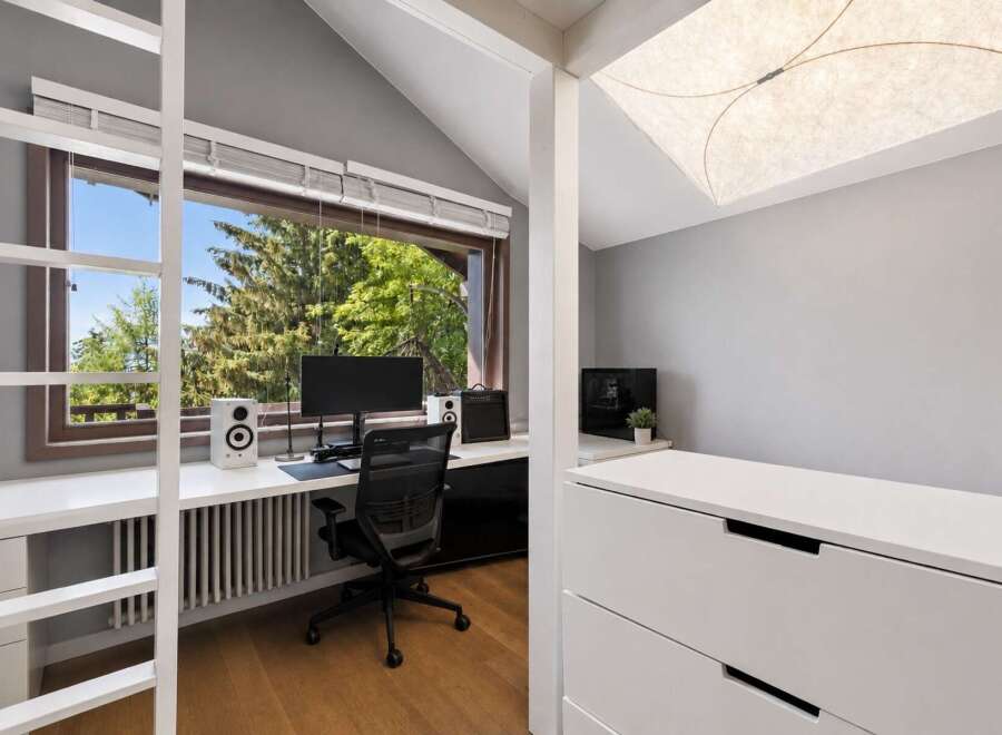 This modern home office features a large window with a scenic view of trees, providing ample natural light.