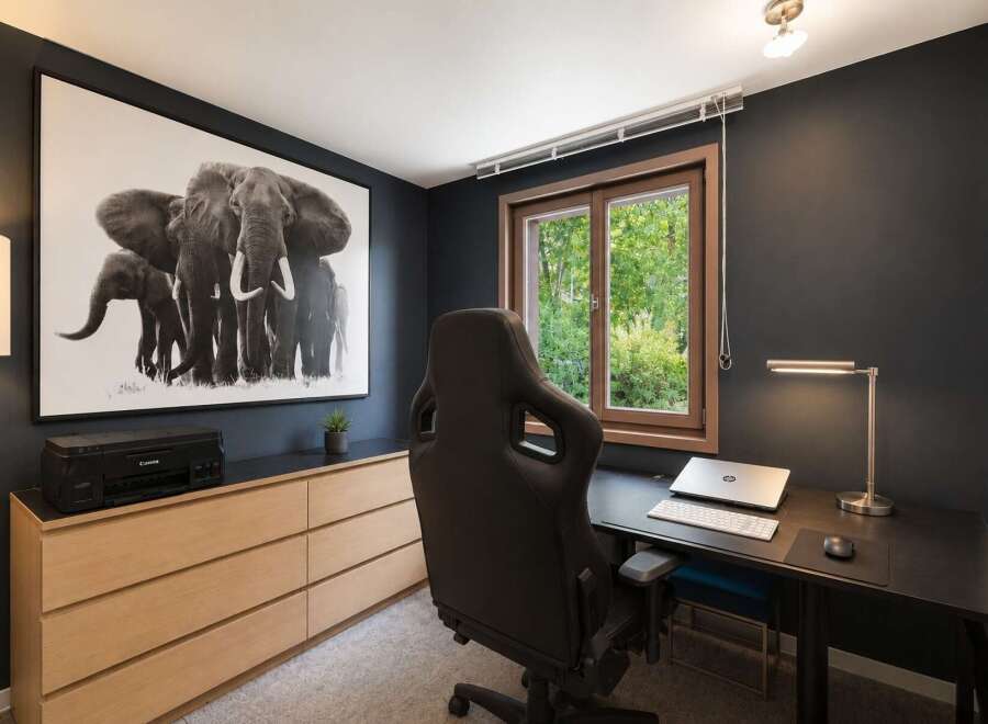 This modern home office features a striking black and white elephant artwork that adds a touch of drama to the dark grey walls.