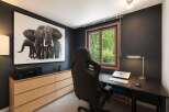 This modern home office features a striking black and white elephant artwork that adds a touch of drama to the dark grey walls.